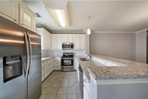a kitchen with granite countertop a refrigerator and microwave