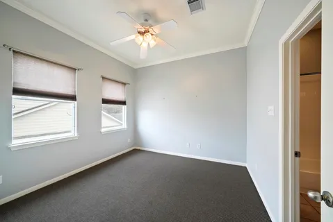 an empty room with windows and chandelier fan