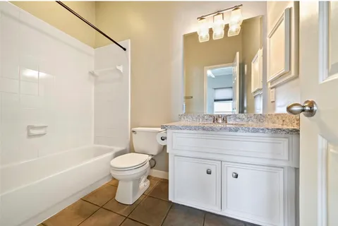 a bathroom with a granite countertop toilet a sink and a bathtub
