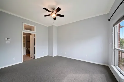 an empty room with windows and ceiling fan