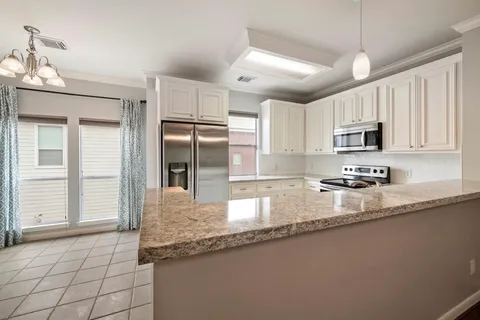 a kitchen with granite countertop a sink a counter top space cabinets and stainless steel appliances