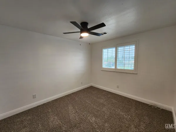 an empty room with a window and a fan