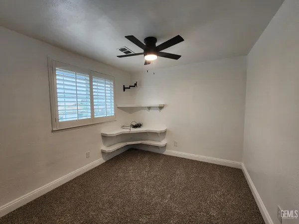 an empty room with windows and fan