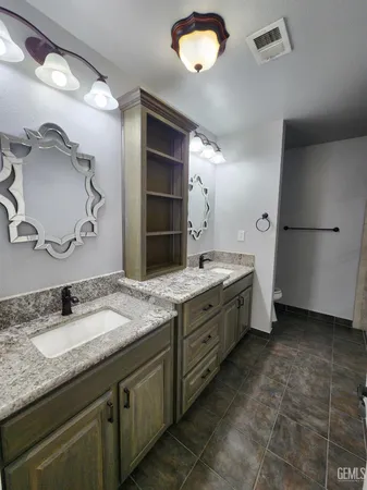 a bathroom with a granite countertop double vanity sink and mirror