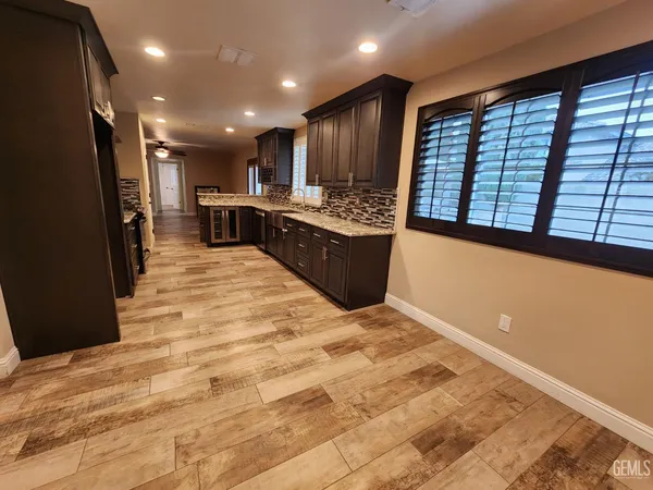 a large hall with stainless steel appliances wooden floor and a large window