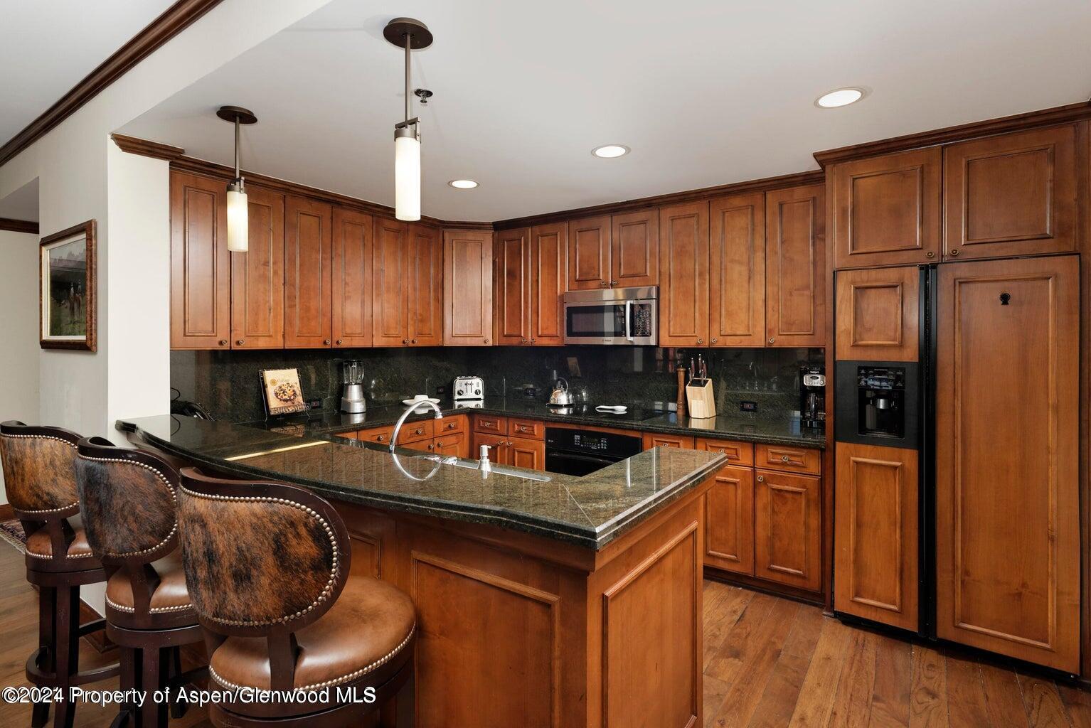 75 Prospector Road, Unit 840610 Aspen, CO 81611 - Photo 6 of 29 a kitchen with stainless steel appliances granite countertop a stove sink refrigerator and cabinets