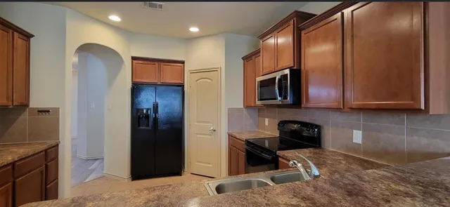a kitchen with stainless steel appliances granite countertop a refrigerator and a sink