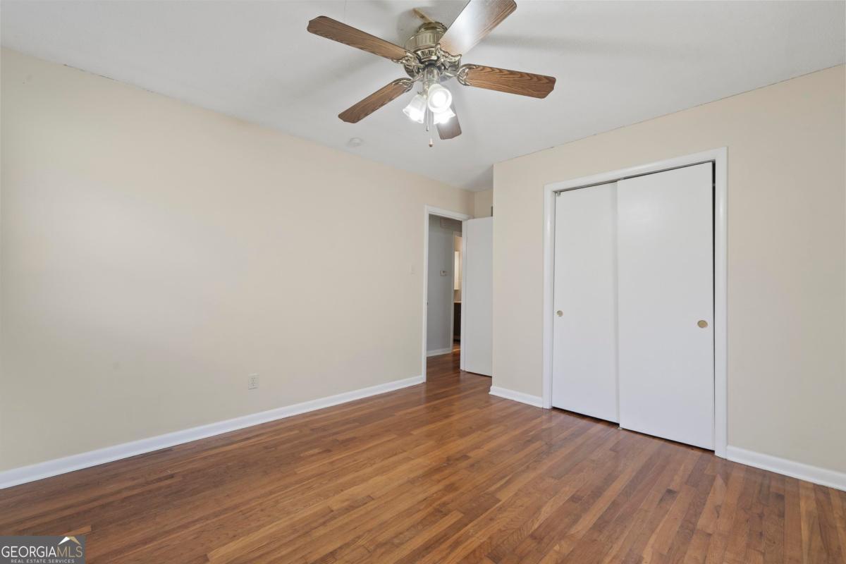 3021 Penfield Road Greensboro, GA 30642 - Photo 33 of 50 a view of an empty room with window a ceiling fan and wooden floor