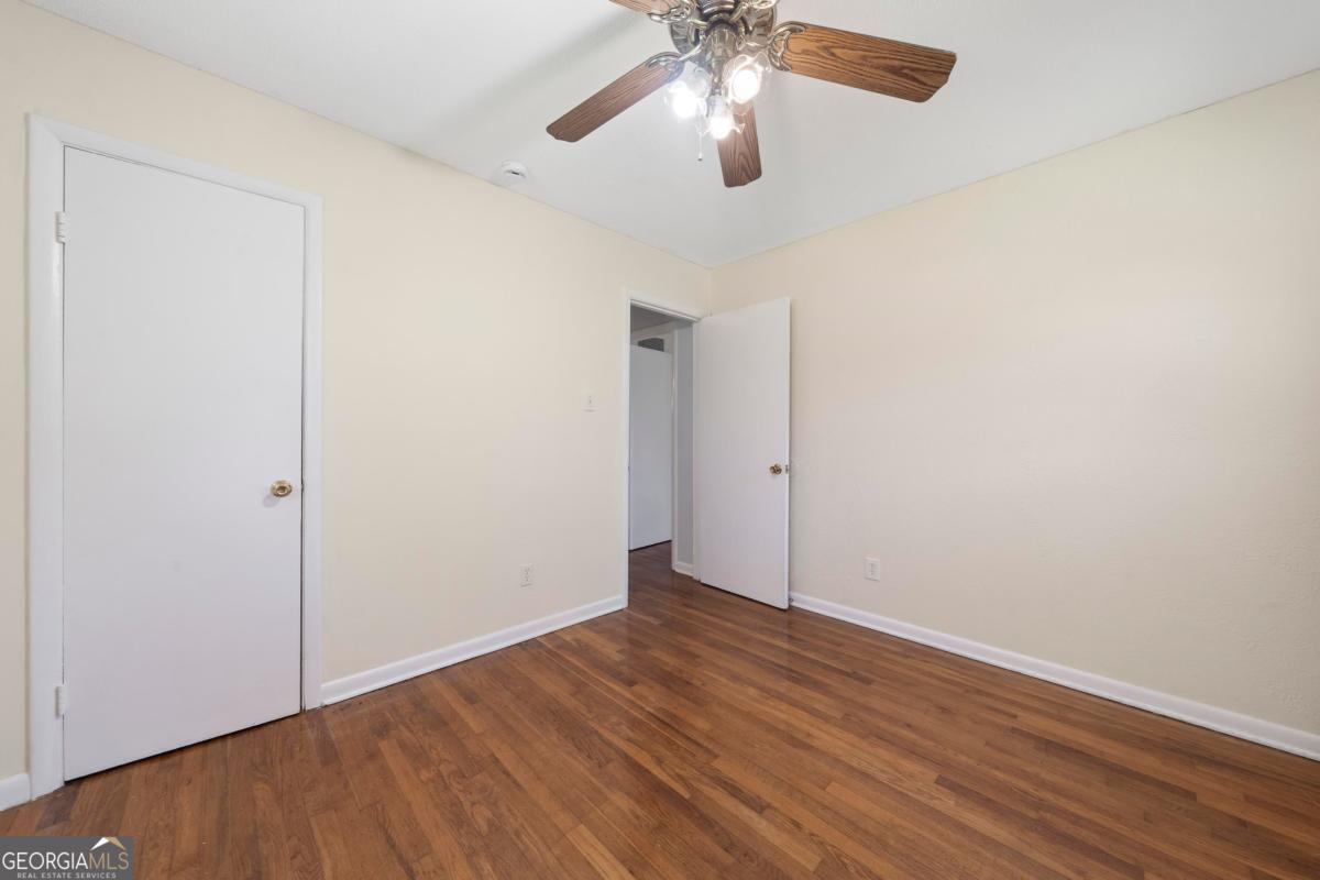 3021 Penfield Road Greensboro, GA 30642 - Photo 35 of 50 an empty room with wooden floor chandelier fan and closet area
