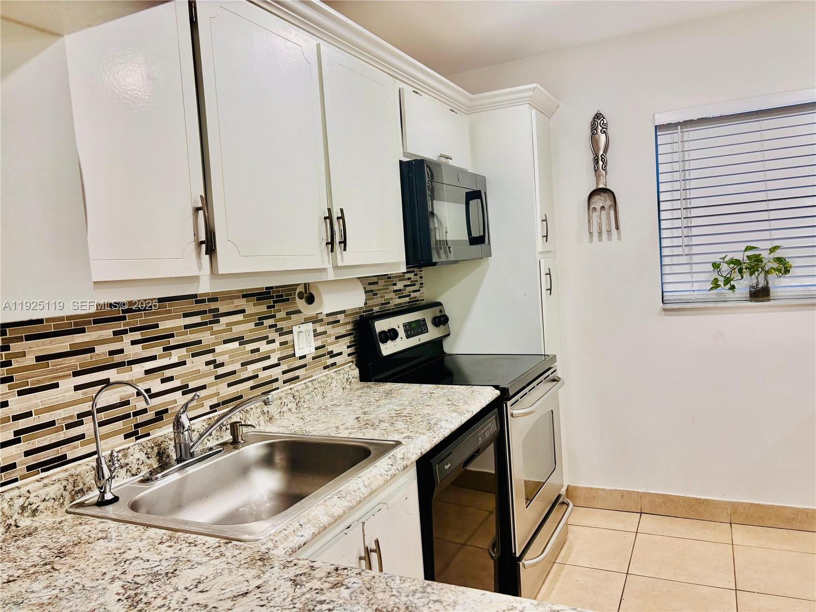 8350 Sands Point Boulevard, Unit E104 Tamarac, FL 33321 - Photo 1 of 13 a kitchen with granite countertop a sink and a stove top oven