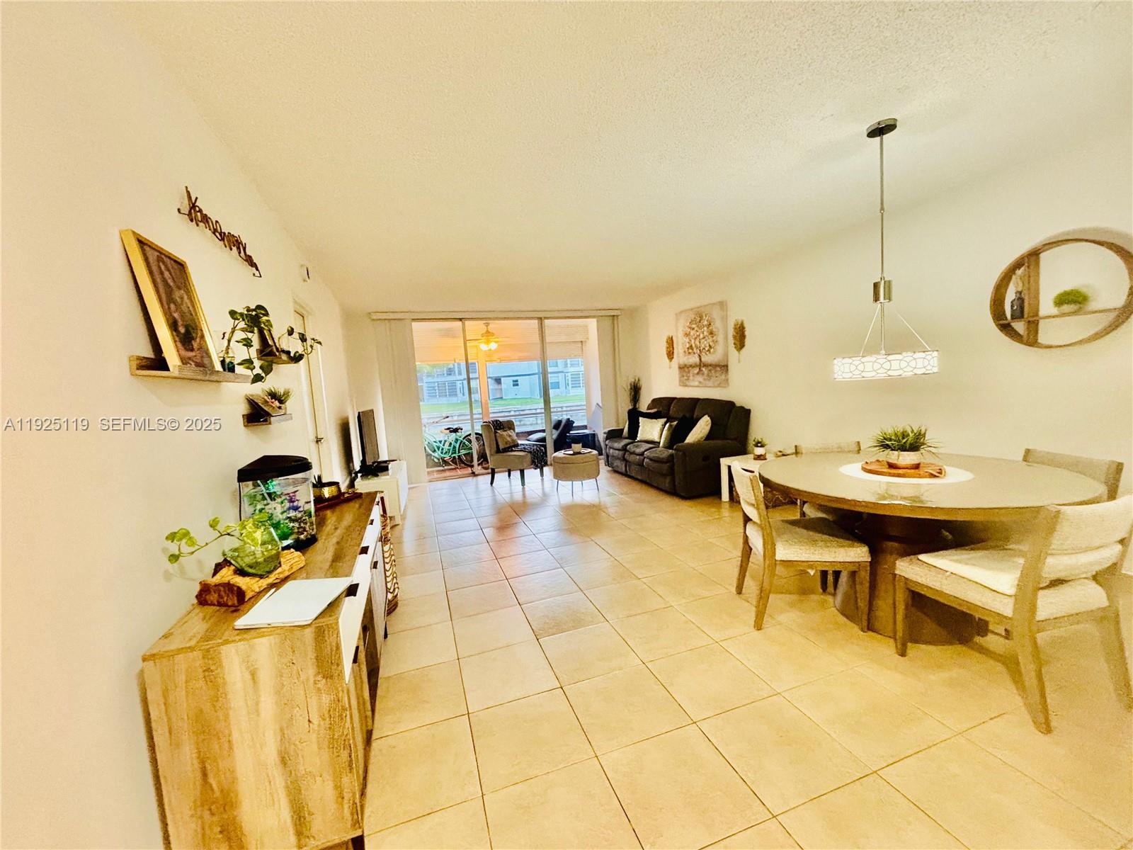 8350 Sands Point Boulevard, Unit E104 Tamarac, FL 33321 - Photo 6 of 13 a living room with furniture and a chandelier