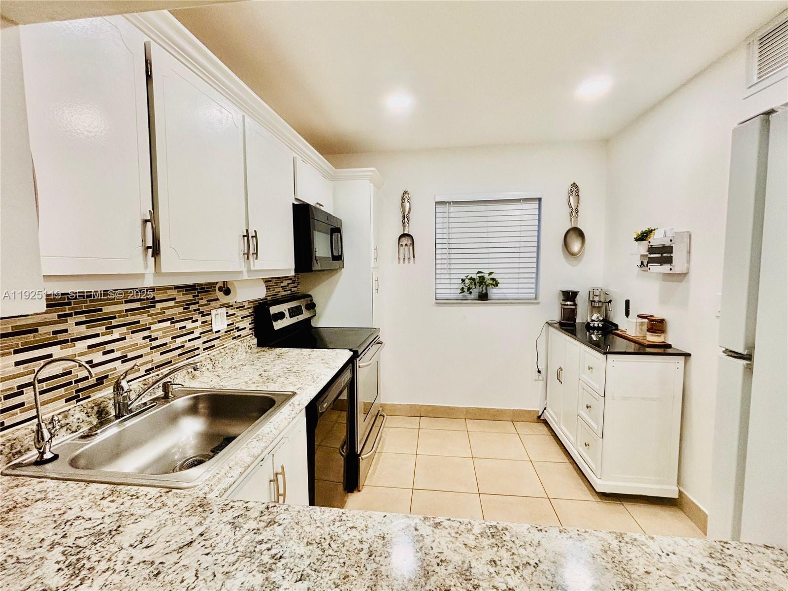 8350 Sands Point Boulevard, Unit E104 Tamarac, FL 33321 - Photo 10 of 13 a kitchen with granite countertop a sink a stove and cabinets