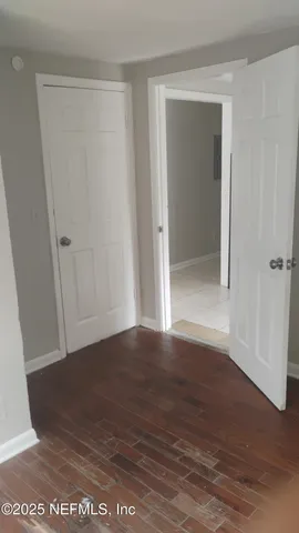 a view of an empty room with wooden floor and closet