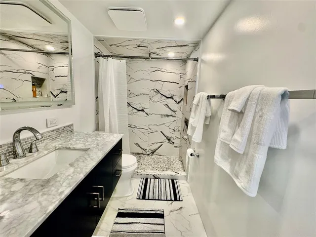 a bathroom with a granite countertop shower sink and vanity