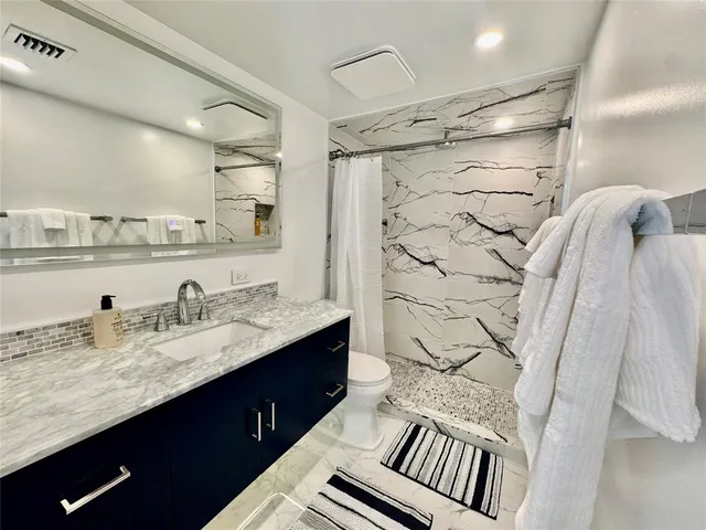 a bathroom with a granite countertop sink vanity mirror and shower