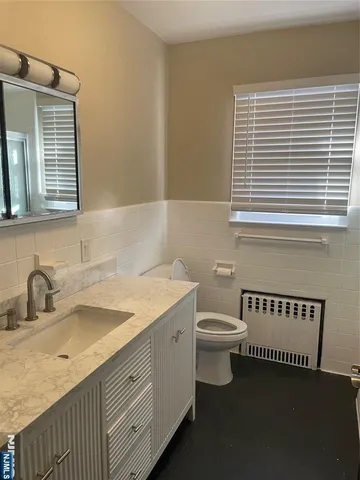 a bathroom with a granite countertop sink and a toilet