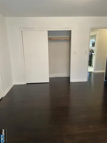 a view of an empty room with wooden floor and closet