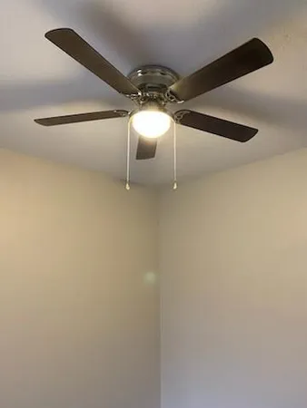 an empty room with wooden floor and fan