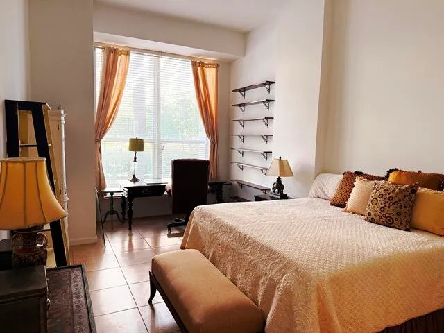 a bedroom with a bed a lamp and a large window