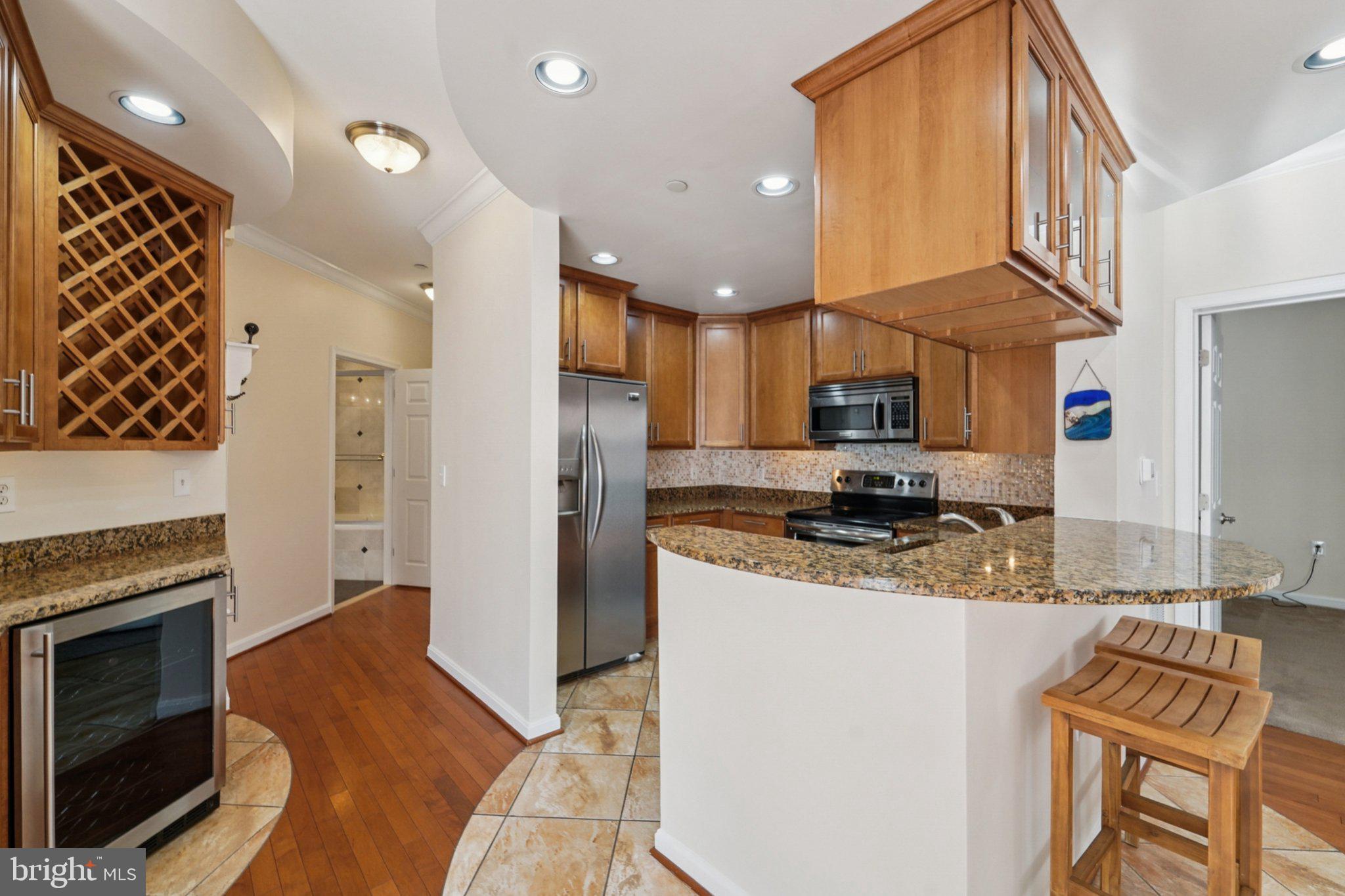 23 Pierside Drive, Unit 118 Baltimore, MD 21230 - Photo 13 of 32 a kitchen with stainless steel appliances granite countertop a refrigerator a stove and a sink with wooden floor