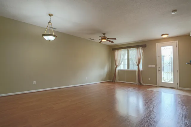an empty room with wooden floor and windows