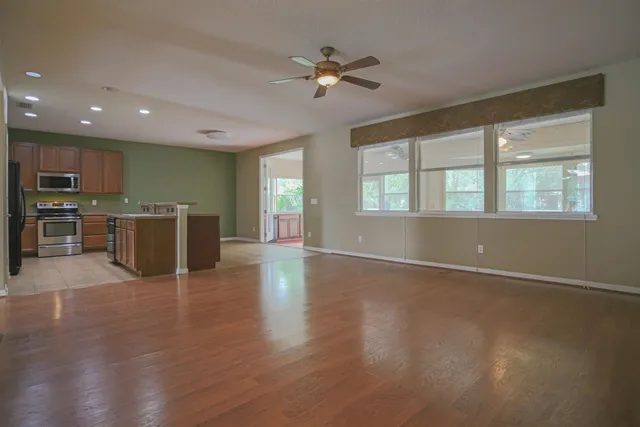 an open kitchen with wooden floor and stainless steel appliances