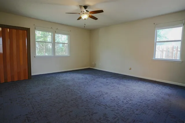 an empty room with windows and ceiling fan