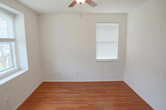 an empty room with a window and a chandelier fan