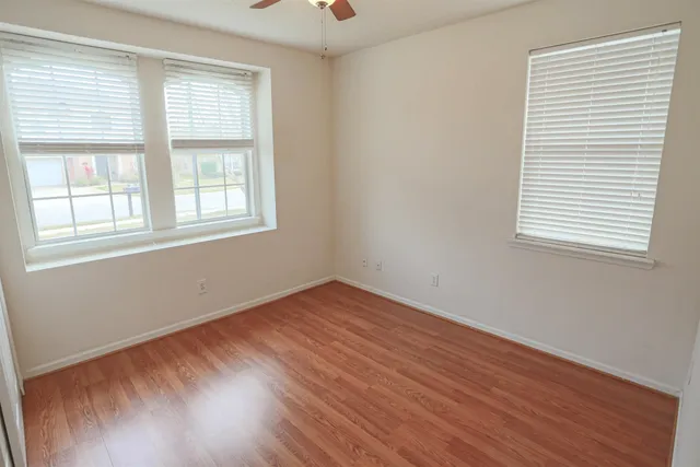 an empty room with wooden floor and windows