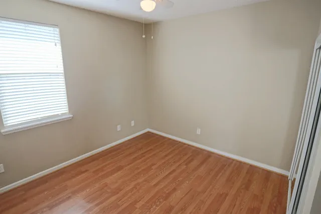 an empty room with wooden floor and windows