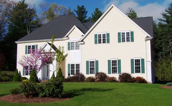 a view of a white house next to a yard with plants and trees
