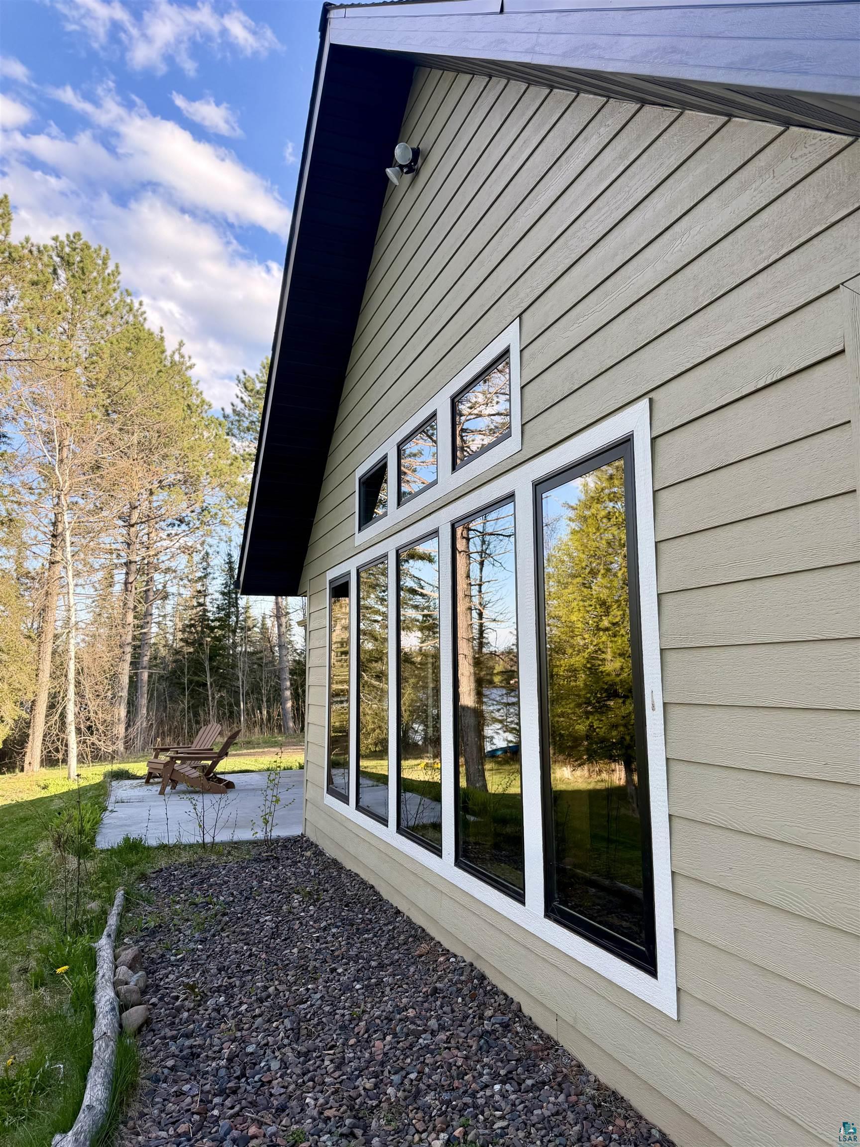 5274 Marble Lake Road Two Harbors, MN 55616 - Photo 55 of 79 Light-colored horizontal siding exterior featuring a dark trim and a series of tall, framed windows