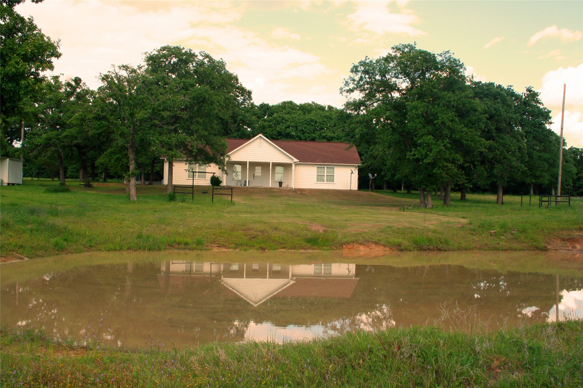 831 Barrons Ridge Wilson, OK 73463 - Photo 46 of 47 Expansive pond with tranquil reflections, set against a backdrop of a single-story residence