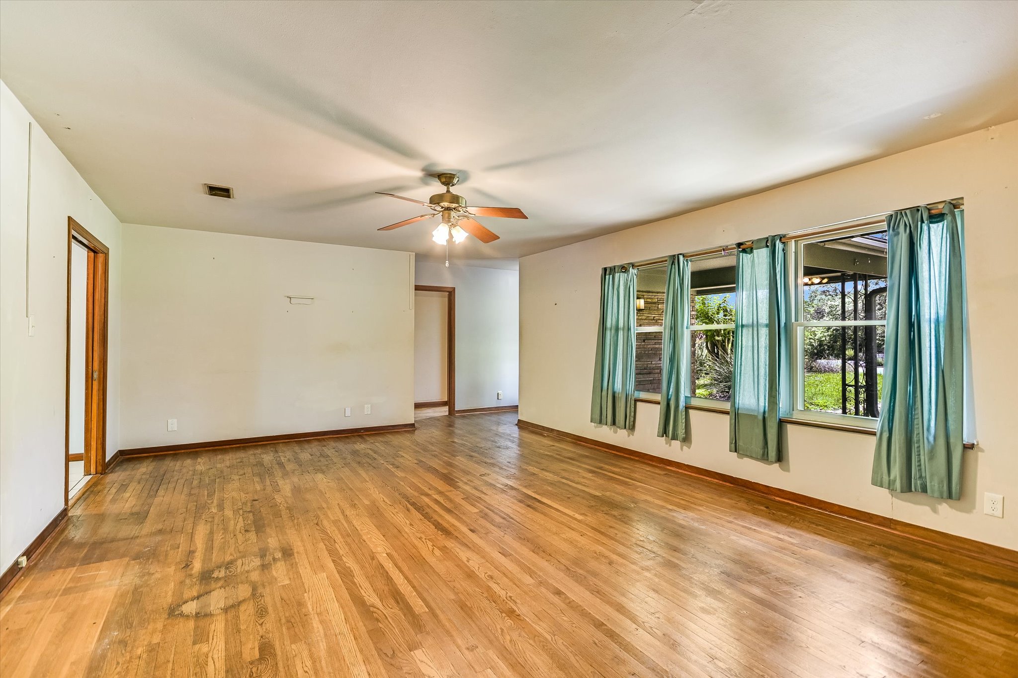 502 Sunset Circle Austin, TX 78704 - Photo 7 of 27 Spacious living room featuring hardwood floors, multiple windows, a ceiling fan, and wood-burning fireplace