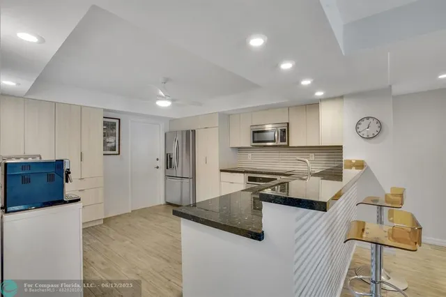 a living room with stainless steel appliances furniture and a flat screen tv