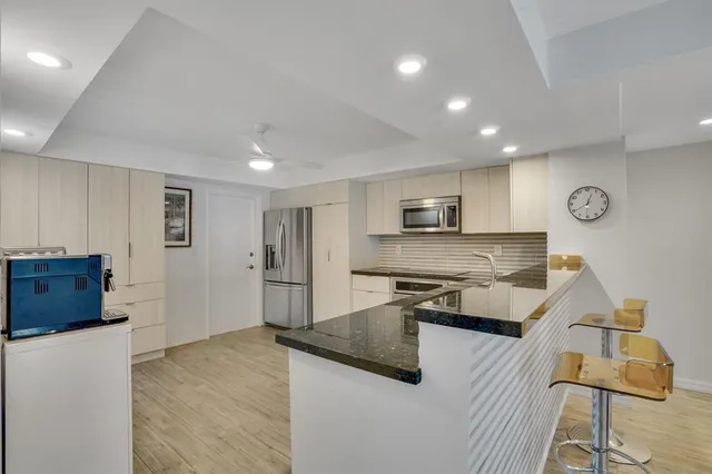 a kitchen with stainless steel appliances kitchen island granite countertop a sink a stove and a refrigerator