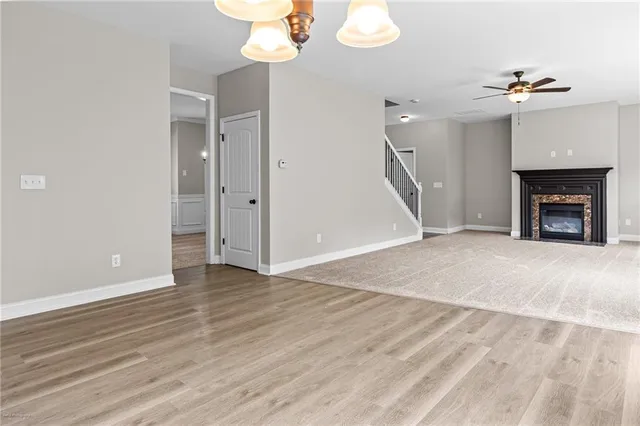 a view of an empty room with wooden floor fireplace and a window