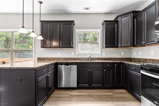 a kitchen with granite countertop a stove a sink and a microwave