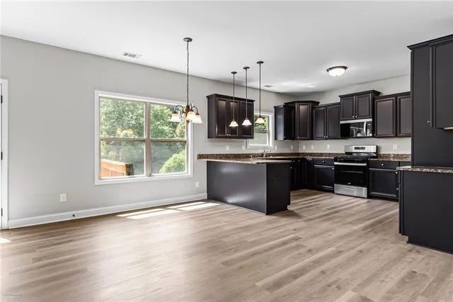 a kitchen with stainless steel appliances granite countertop a refrigerator a sink dishwasher a stove and a microwave oven on granite countertops