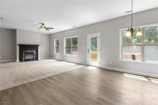 an empty room with windows fireplace and wooden floor