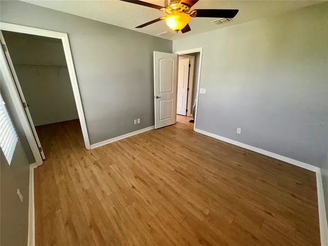 an empty room with wooden floor fan and windows