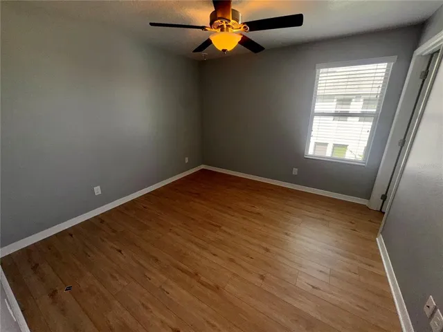 an empty room with windows and a chandelier fan