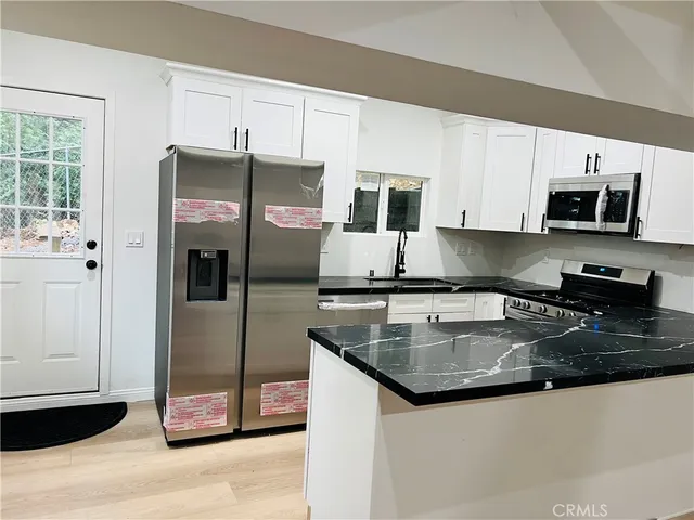 a kitchen with stainless steel appliances granite countertop a refrigerator a stove a sink a microwave and cabinets