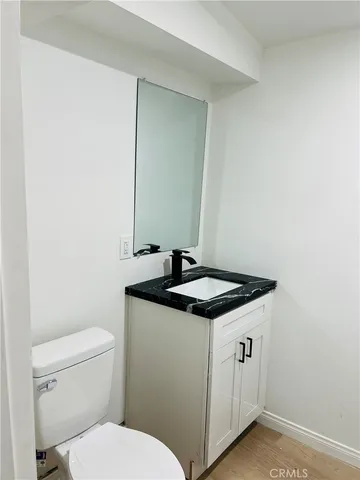 a bathroom with a granite countertop sink a toilet and a mirror