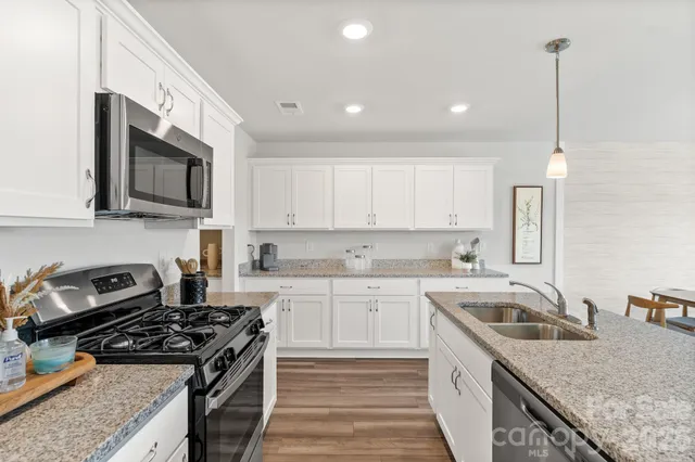 a kitchen with stainless steel appliances granite countertop a sink stove and cabinets