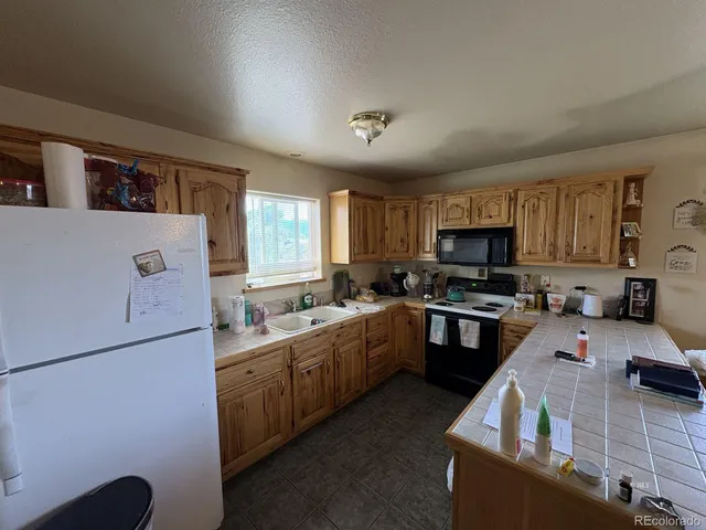 a kitchen with stainless steel appliances granite countertop a sink a stove top oven a refrigerator a sink dishwasher with a dining table and chairs