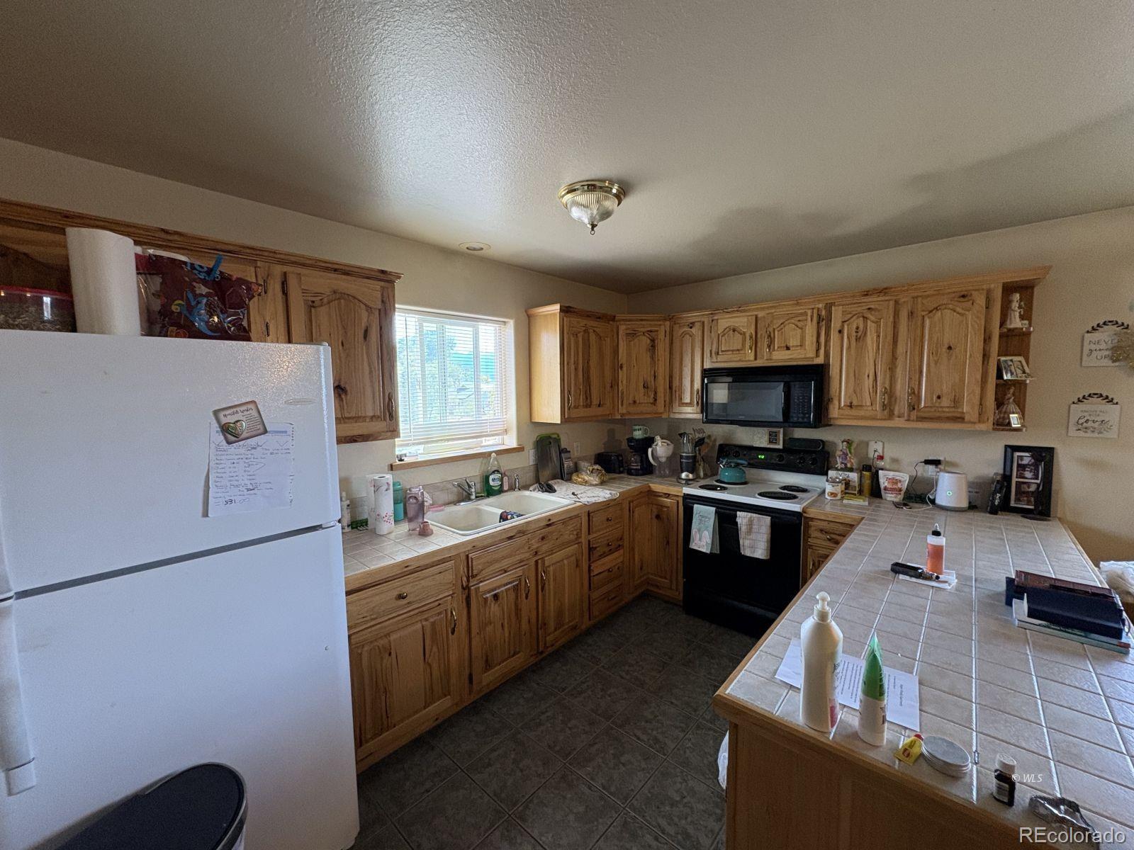 702 Main Street Silver Cliff, CO 81252 - Photo 18 of 20 a kitchen with stainless steel appliances granite countertop a sink a stove top oven a refrigerator a sink dishwasher with a dining table and chairs