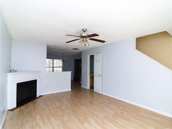 a view of a livingroom with a fireplace a ceiling fan and wooden floor