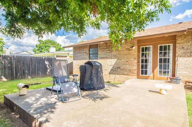 a view of a backyard with table and chairs and a large tree