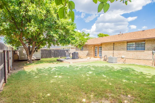 a view of a house with backyard and a tree